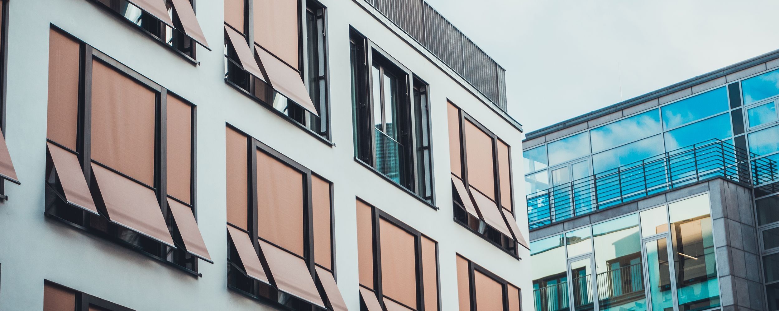 Eine Aufnahme von Hochhäusern mit vielen Fenstern und Rollläden, im Hintergrund ein Balkon